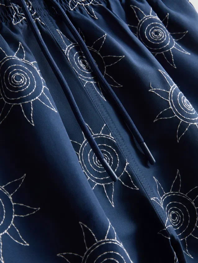Broderade badshorts med solmotiv