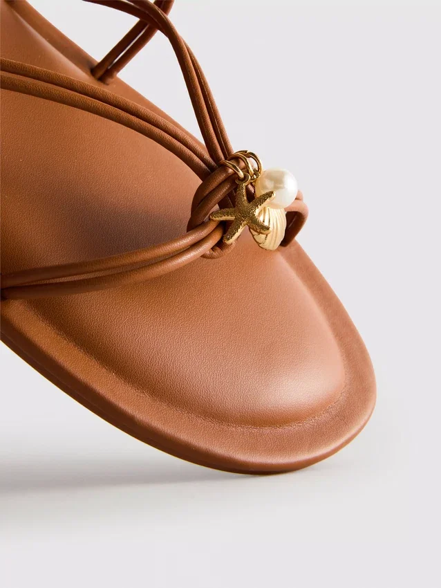Paula Echevarría sandaler med remmar och charm